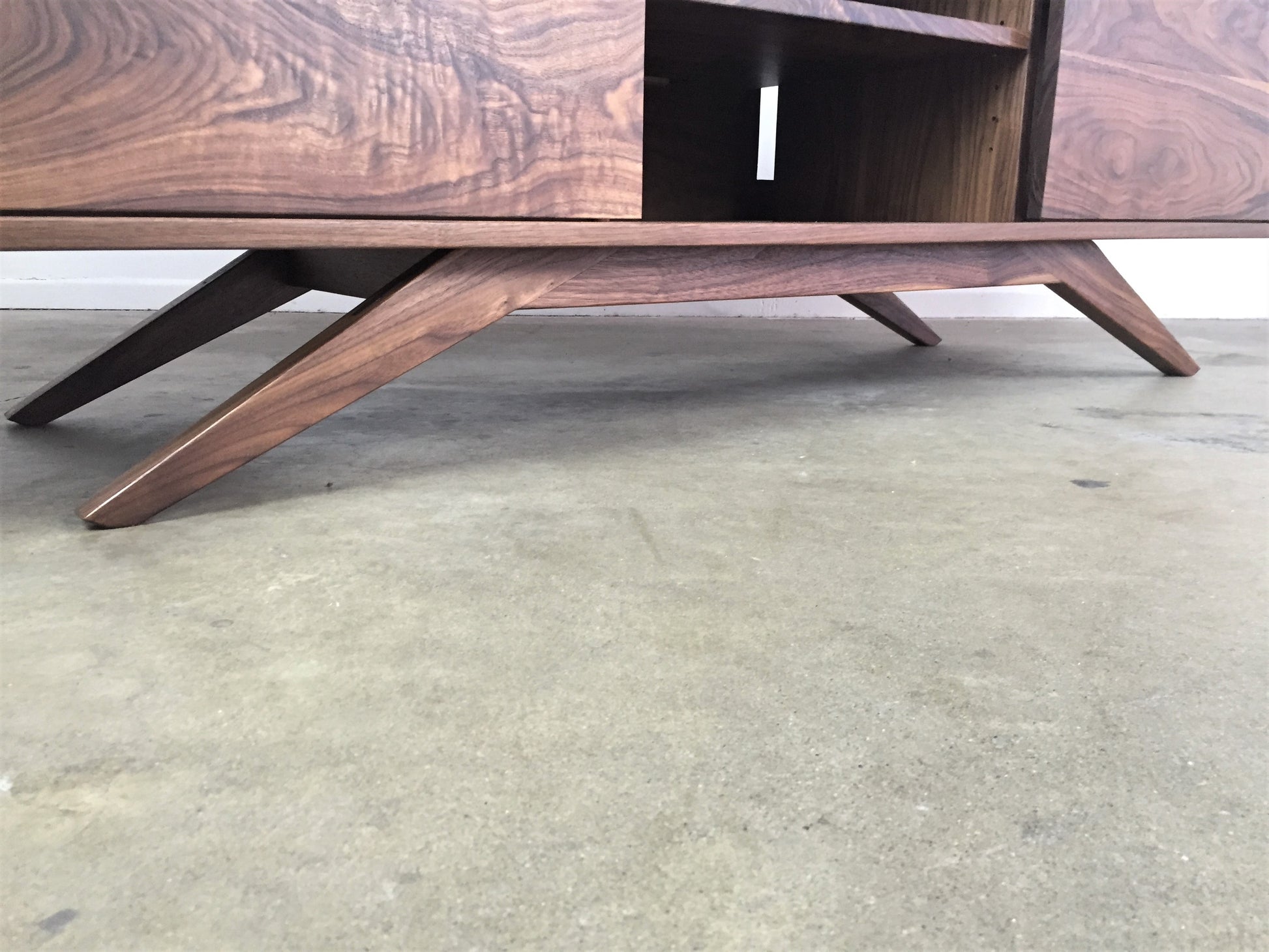 Close-up view of the BlackMo console legs, showcasing sleek, angled, and tapered walnut construction. The legs are designed in a mid-century modern style, providing sturdy support while adding an elegant, sculptural touch to the piece