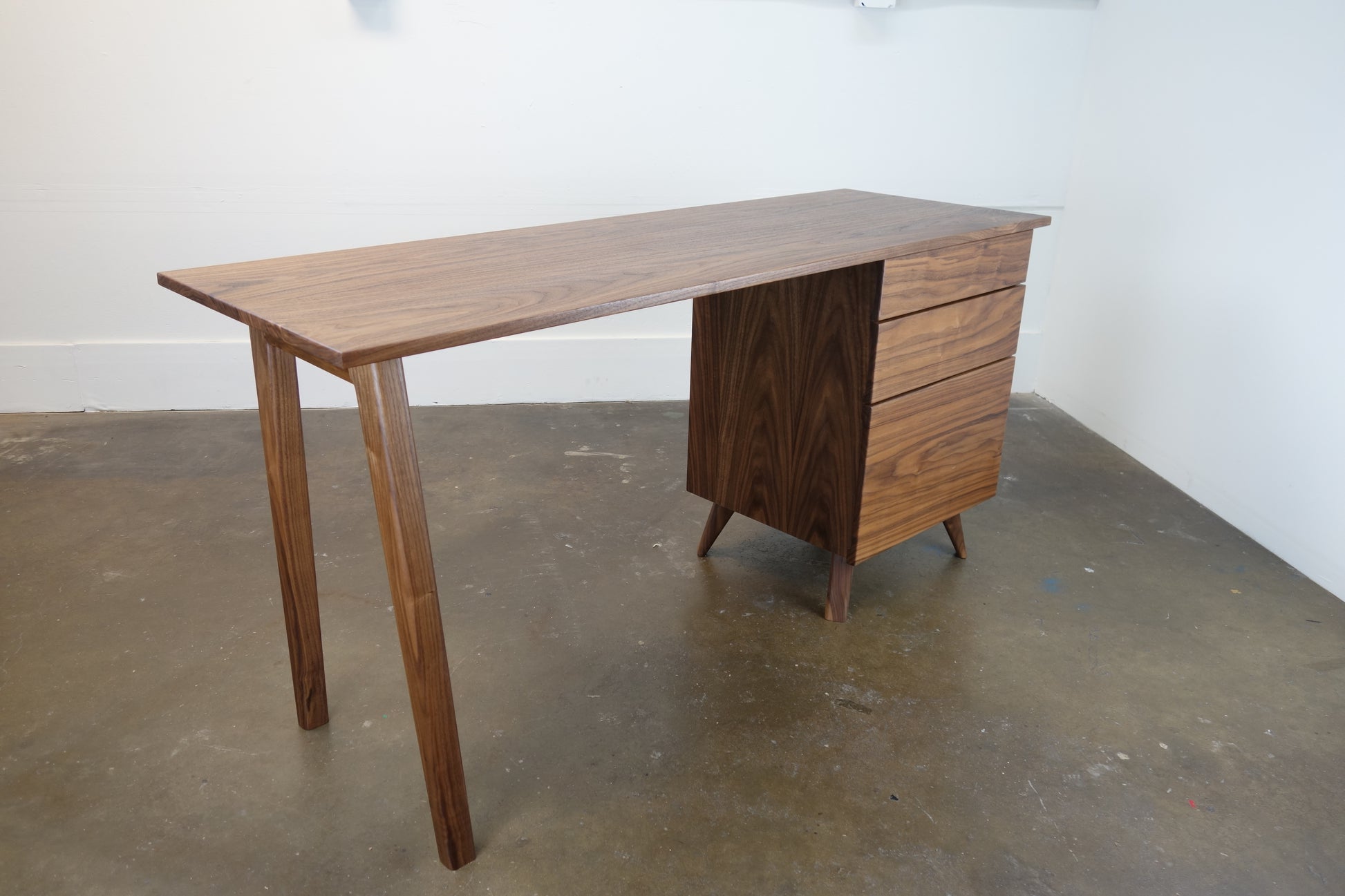 Side view of the Cosmo desk showcasing its minimal design, smooth walnut construction, and heirloom-quality craftsmanship