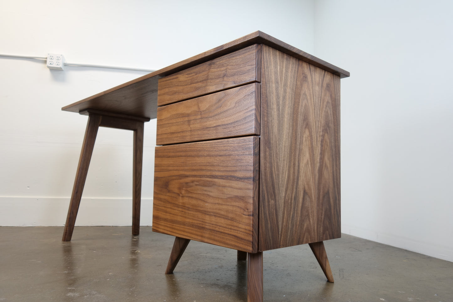 Side view of the Cosmo desk showcasing its minimal design, smooth walnut construction, and heirloom-quality craftsmanship