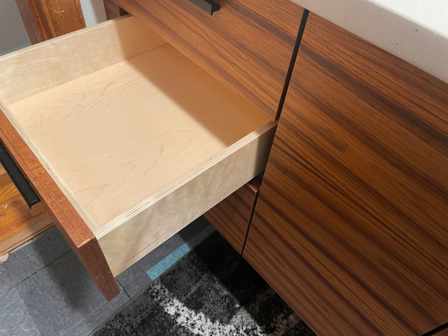 Close-up of the floating vanity’s drawer bank with smooth undermount self-closing slides and prefinished maple interior