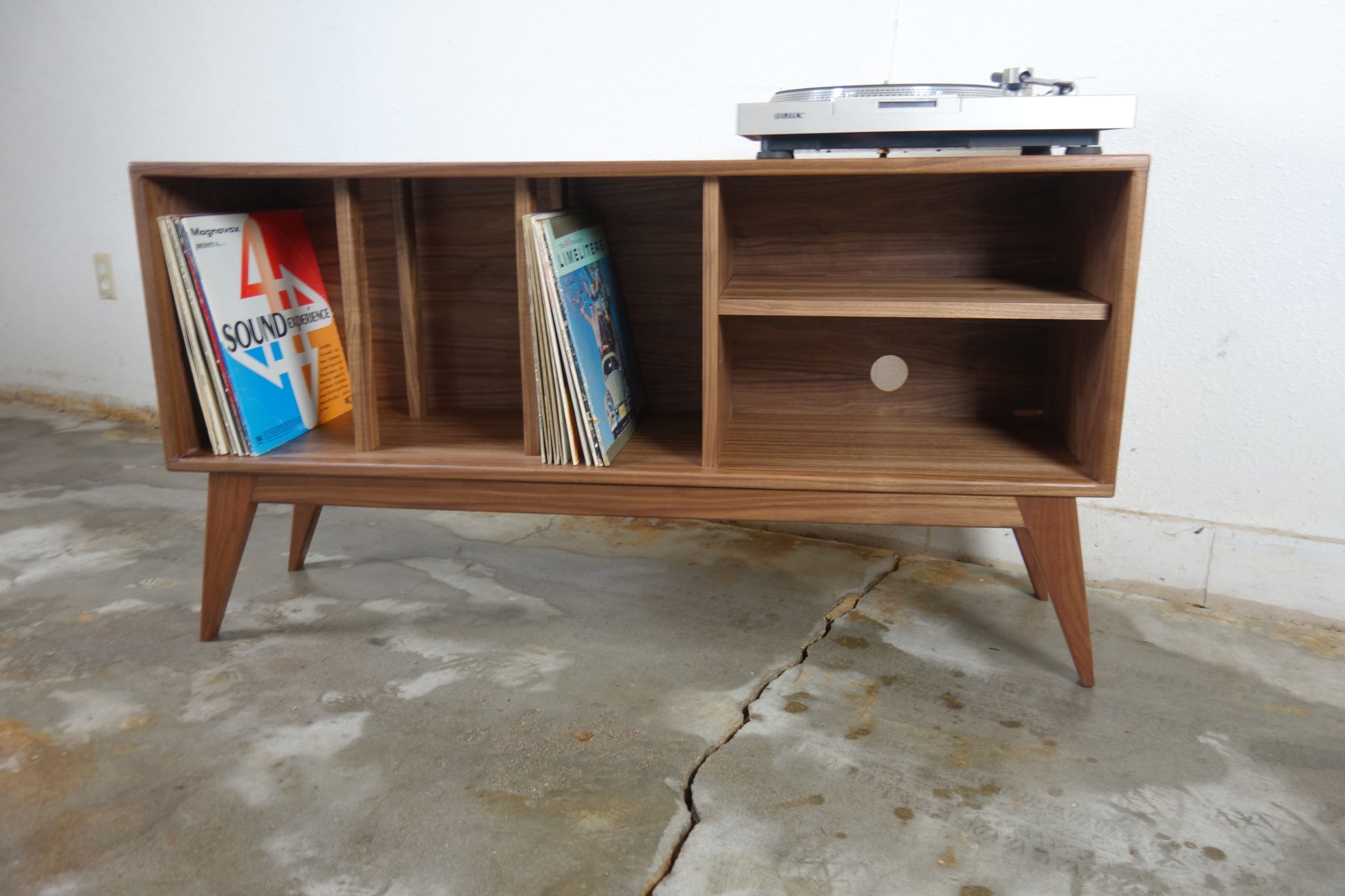 Front view of the K Blast console, handcrafted in walnut with mid-century modern design, featuring record storage and an adjustable shelf