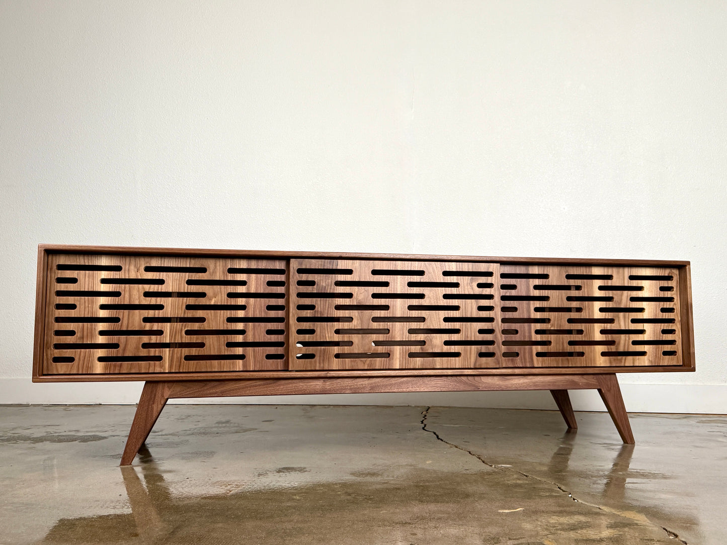 Walnut media console with clean lines and handcrafted mid century modern styling.