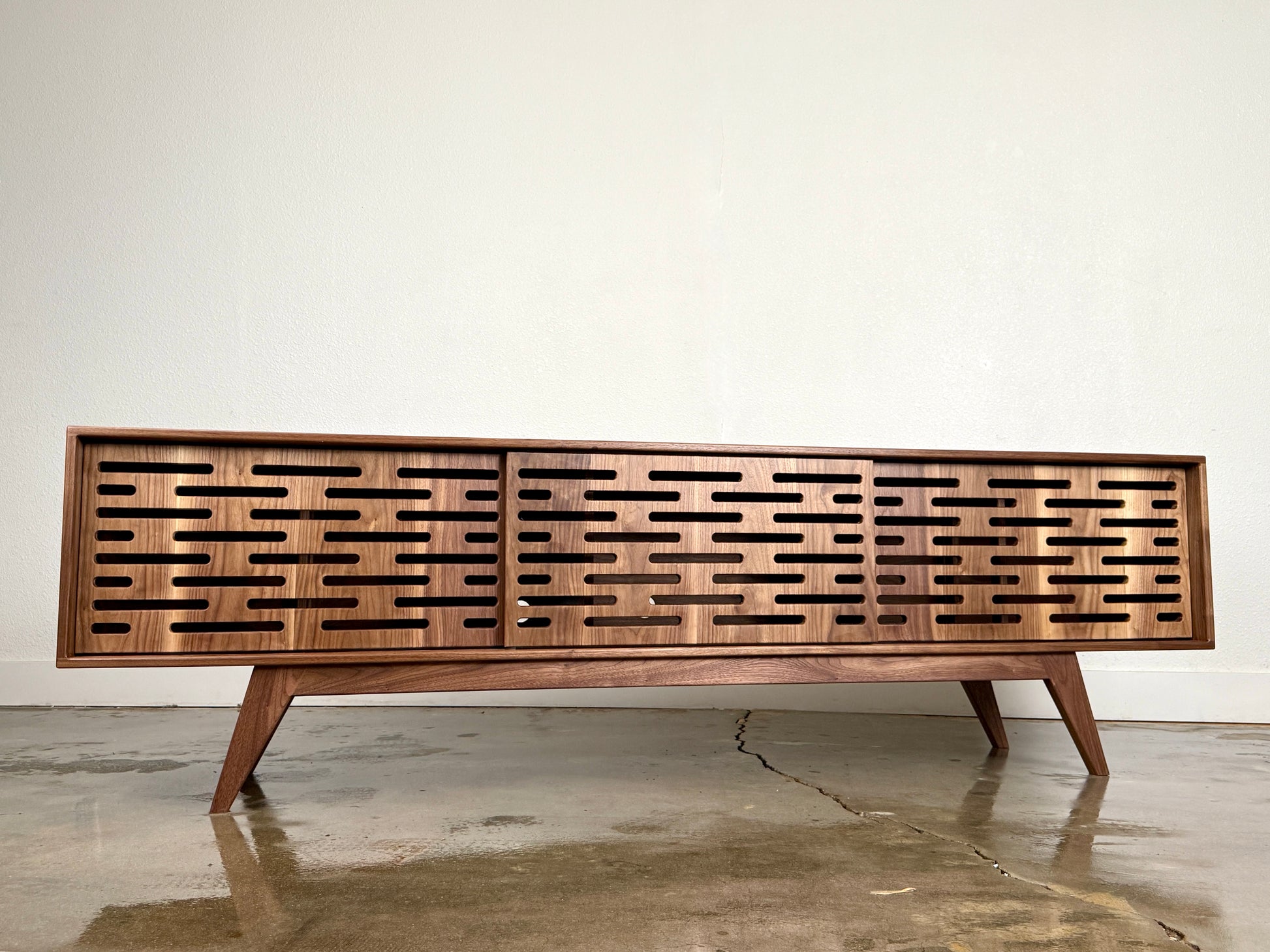 Walnut media console with clean lines and handcrafted mid century modern styling.
