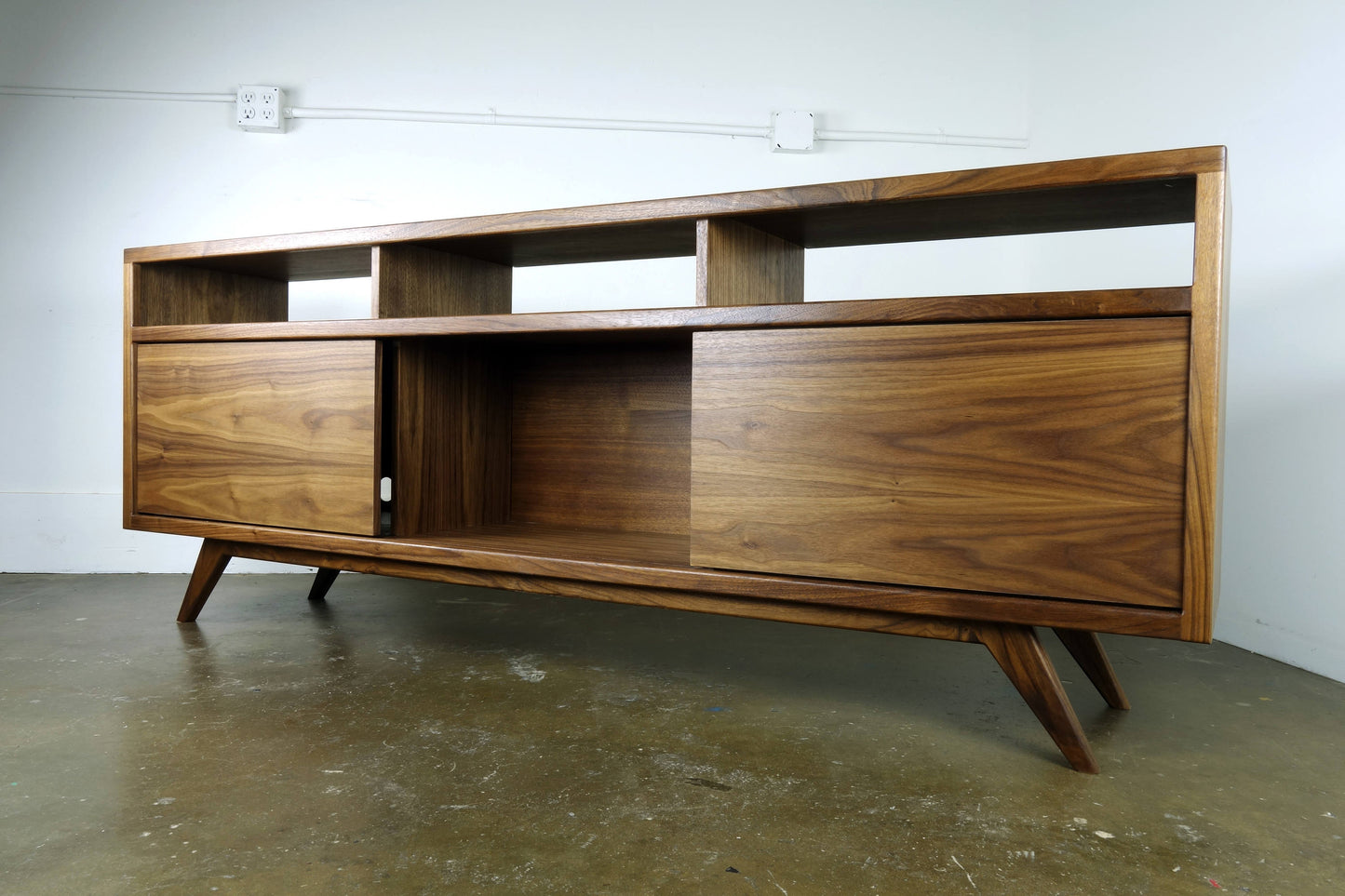 Front view of the SpaceDust console, hand-built from solid and veneer walnut with two sliding doors and mid-century modern design