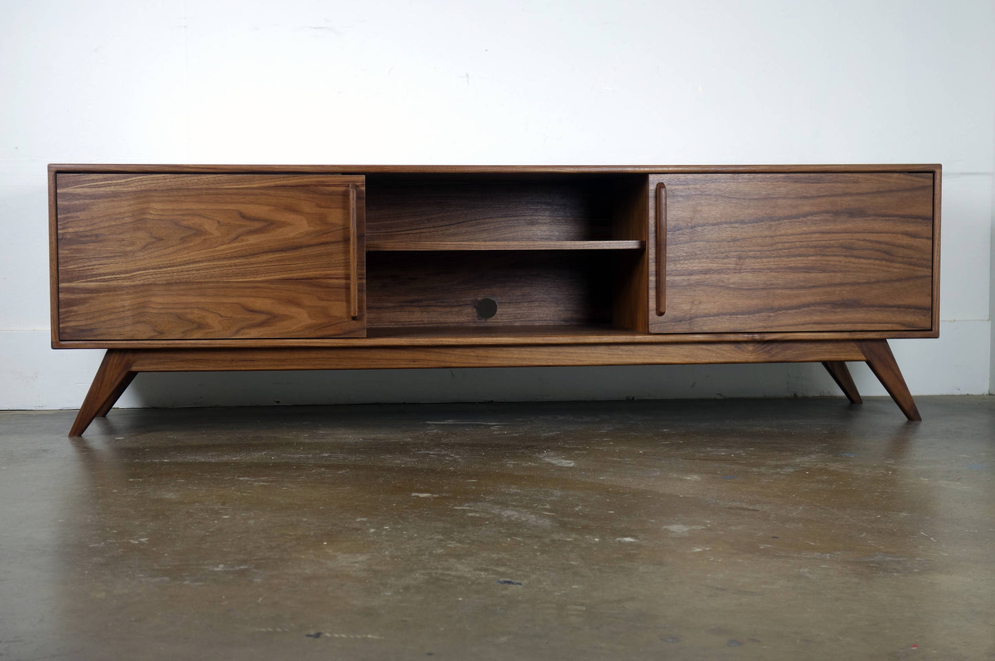 Mid century modern walnut TV console with sliding doors and clean architectural lines.
